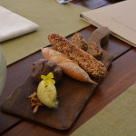 A wooden cutting board with bread and other food on it.