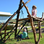 Two children are playing on a wooden structure.