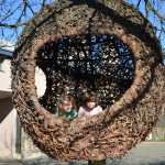 Two children are standing in a circular sculpture.