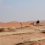 A man and two children are standing on the desert.