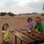 A man and two girls sitting at a table with beer.