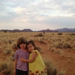 Two children are hugging in the desert.