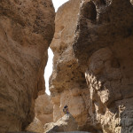 A person standing on the side of a rock formation.