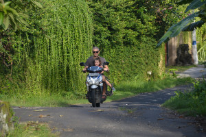 A man and child riding on the back of a motorcycle.